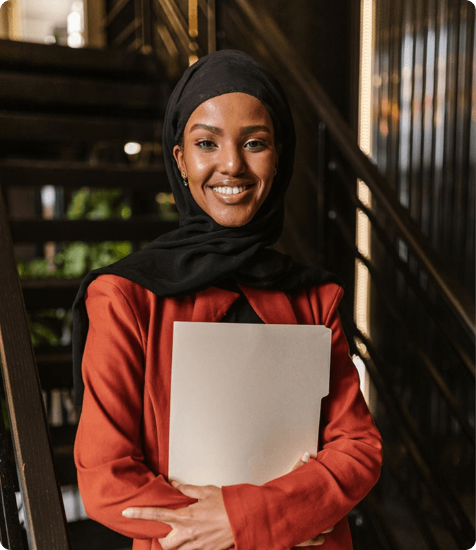 A woman smiling and holding a laptop