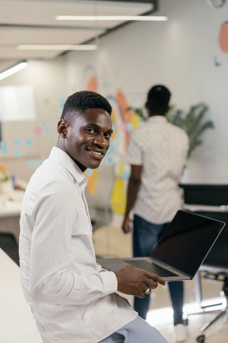 A man smiling and holding a laptop at the office