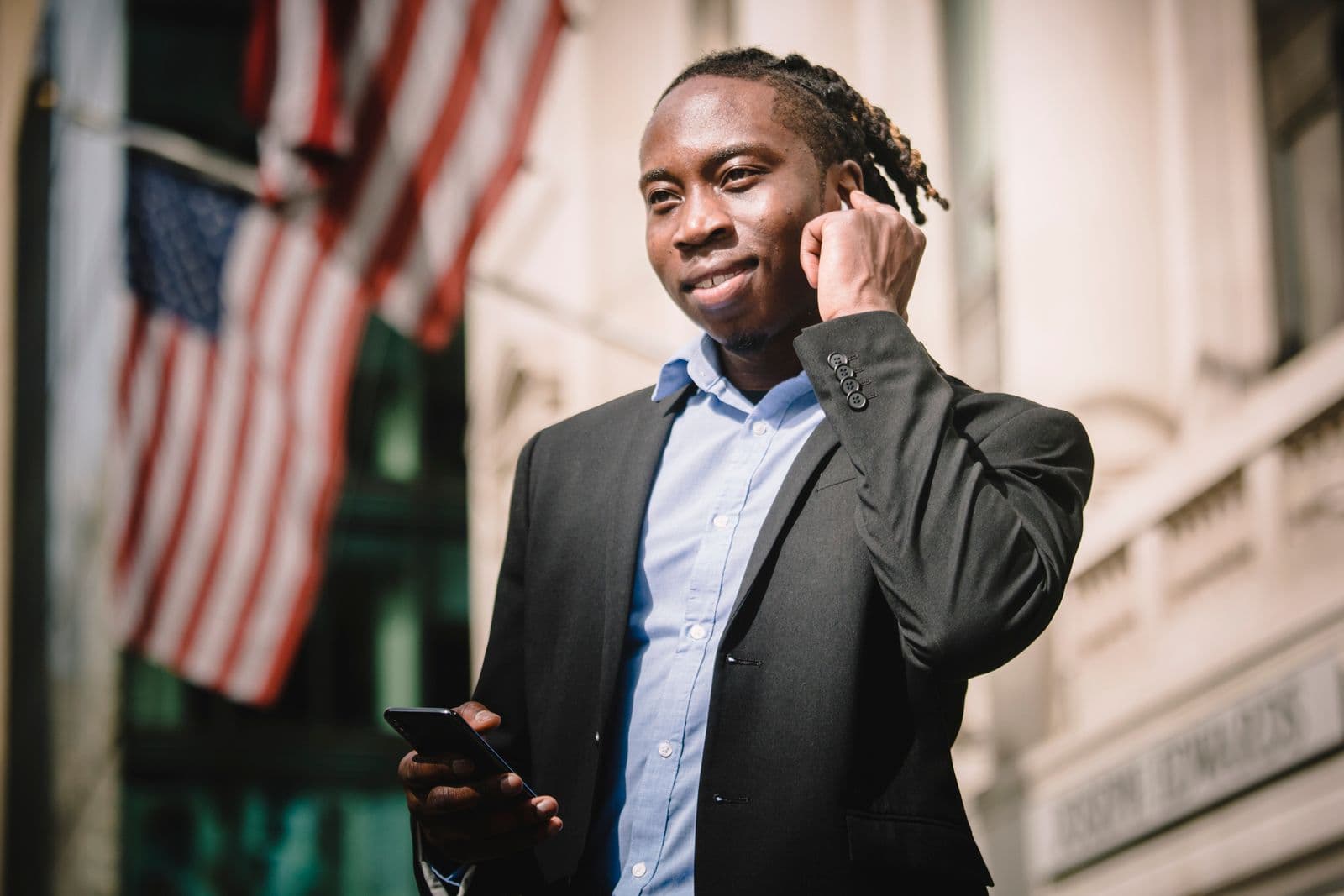 A man in a suit speaking through an earbud while holding his phone