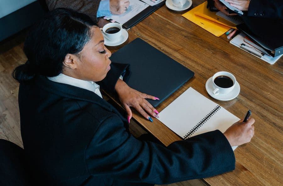 A businesswoman writing notes alongside her laptop