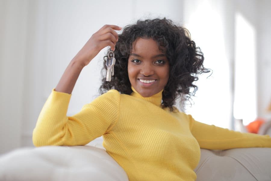 A smiling woman holding the keys to her home